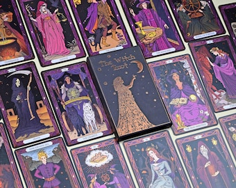 Op de afbeelding: Een tarotkaartspel met een zwarte doos met de titel "The Witch Tarot". De kaarten hebben illustraties met paarse, gouden en zwarte randen. De kaarten tonen verschillende figuren en symbolen.