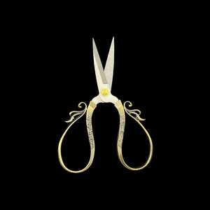 Puede incluir: Tijeras doradas con mangos ornamentados y hojas plateadas. Los mangos presentan delicados diseños florales y de volutas. Las tijeras están sobre un fondo negro sólido, resaltando sus elegantes detalles. Una herramienta clásica para manualidades o costura.