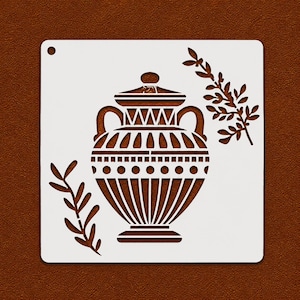 Peut inclure: Un pochoir blanc représentant une amphore brune stylisée avec des anses, un couvercle et des motifs décoratifs. Deux brins de feuilles encadrent le vase. Le pochoir est sur un fond marron.