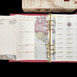 May include: A pink traveler's journal with a gold ring binder. The cover features a map of the United States with a list of national parks on the right side.