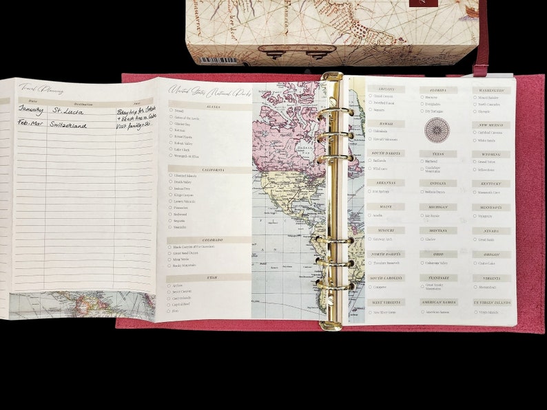 May include: A pink traveler's journal with a gold ring binder. The cover features a map of the United States with a list of national parks on the right side.