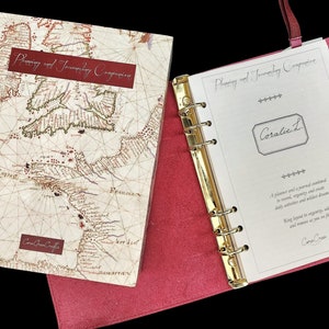 May include: A red leather bound journal with a gold ring binder. The cover features a vintage map with the text "Planning and Journeying Companion". The inside page has the text "Coralie L" and "A planner and a journal combined to record, organize and create daily activities and wilder dreams.  Keep track of your goals and memories as you set off on your journey."