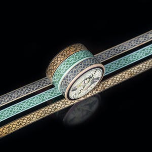 May include: Three rolls of decorative washi tape with a Celtic knot design. The tape is in shades of brown, green, and blue.