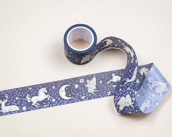 May include: Decorative washi tape roll with a dark blue background and a repeating pattern of white mythical creatures, including deer, unicorns, fairies, and moons. The tape is unrolled, showing the design. The roll is on a light beige surface.