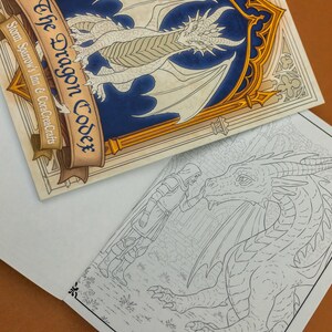 May include: A fantasy-themed coloring book titled "The Dragon Codex" with a detailed dragon illustration on the cover. The open page reveals a black and white line drawing of a dragon and a knight. The book is set against a brown background.