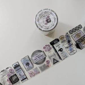 May include: A roll of clear adhesive tape featuring a repeating vintage-style print of apothecary bottles, face powder tins, and floral illustrations in shades of black, white, and purple. The label on the roll reads "KINDHURA'S CRAFTS STUDIO".