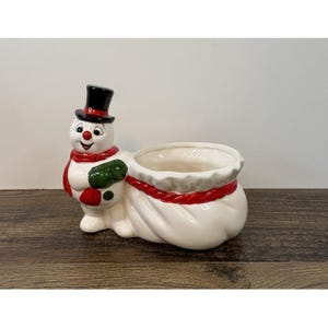 May include: A white ceramic mug with a black handle and the text "But First, Coffee" in a black, handwritten-style font. The mug is on a white surface.