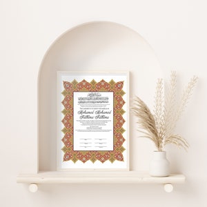 May include: A white framed Islamic wedding certificate with a red and gold ornate border. The text reads "This agreement is to certify the marriage of Mohamed Mohamed and Fathima Fathima".