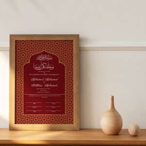 May include: A framed red and gold Islamic wedding certificate with Arabic calligraphy and the text "This agreement is to certify the marriage of Mohamed Mohamed and Fathima Mohamed".