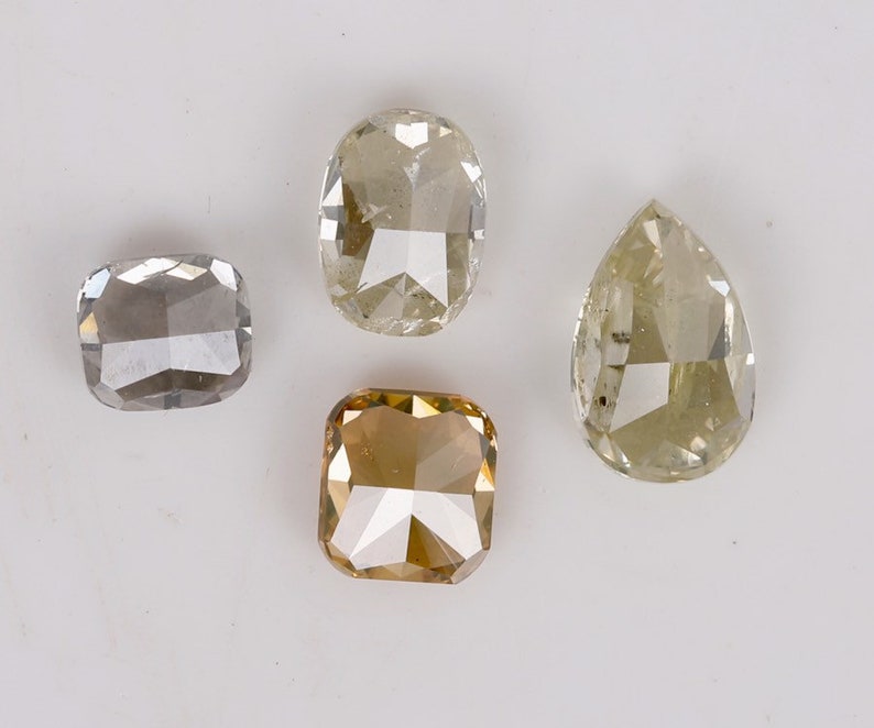Puede incluir: Cuatro diamantes sueltos de diferentes formas y colores. Un diamante en forma de pera, un diamante cuadrado, un diamante rectangular y un diamante ovalado.