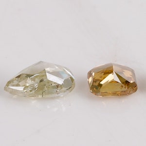 Puede incluir: Cuatro diamantes sueltos de diferentes tama&ntilde;os y colores. Los diamantes est&aacute;n cortados en una forma &uacute;nica y facetada. Los diamantes est&aacute;n dispuestos en una fila de izquierda a derecha, con el diamante m&aacute;s peque&ntilde;o a la izquierda y el diamante m&aacute;s grande a la derecha. Los diamantes son todos transparentes, pero tienen diferentes tonos de gris, verde y marr&oacute;n.