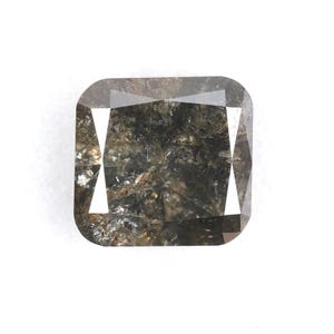 May include: A dark gray, square-shaped, emerald cut diamond with a rough, natural finish.