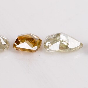 Puede incluir: Cuatro diamantes sueltos de diferentes colores, incluyendo un marr&oacute;n claro, un gris claro, un gris oscuro y un diamante claro. Los diamantes est&aacute;n todos cortados en una forma rectangular ligeramente redondeada similar.