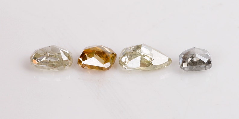 Puede incluir: Cuatro diamantes sueltos de diferentes colores, incluyendo un marr&oacute;n claro, un gris claro, un gris oscuro y un diamante claro. Los diamantes est&aacute;n todos cortados en una forma rectangular ligeramente redondeada similar.