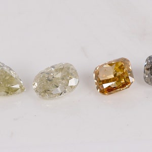 Puede incluir: Cuatro diamantes sueltos de diferentes formas y colores. Un diamante en forma de pera, un diamante redondo, un diamante cuadrado y un diamante coj&iacute;n.