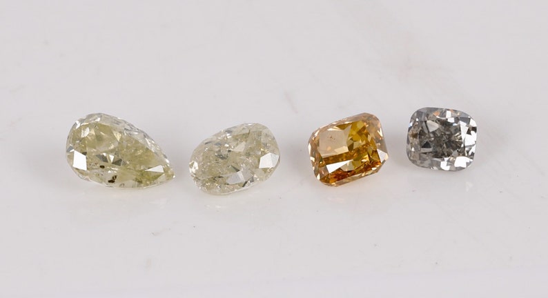 Puede incluir: Cuatro diamantes sueltos de diferentes formas y colores. Un diamante en forma de pera, un diamante redondo, un diamante cuadrado y un diamante coj&iacute;n.