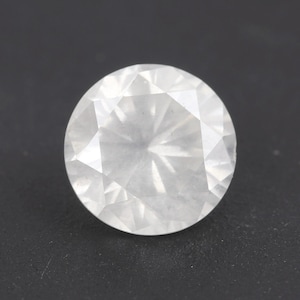May include: A round, faceted, colorless gemstone with a brilliant cut. The gem has a high degree of clarity and reflects light, creating a sparkling effect. The gemstone is set against a dark background.