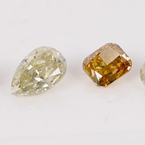 Puede incluir: Cuatro diamantes sueltos de diferentes formas y colores. Los diamantes son gris claro, amarillo claro, marr&oacute;n claro y blanco claro.
