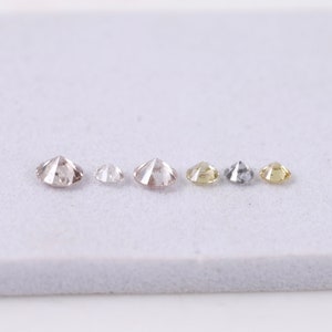 K&ouml;nnte beinhalten: Sechs runde, facettierte Diamanten in verschiedenen Gr&ouml;&szlig;en und Farben, darunter Braun, Wei&szlig;, Gelb und Grau, in einer Reihe auf einer wei&szlig;en Oberfl&auml;che angeordnet.