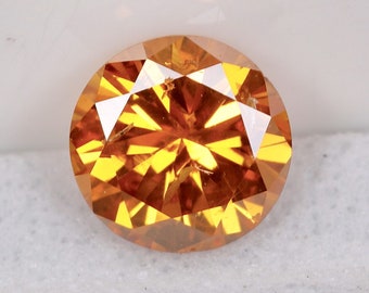 May include: A round, orange diamond gemstone with a faceted cut.