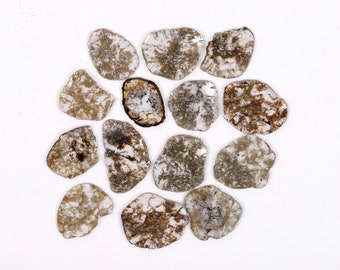 May include: A collection of 14 rough, unpolished, grey and brown diamonds. The diamonds are arranged in a circular pattern on a white background.
