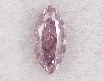 Puede incluir: Un diamante rosa claro con talla marquesa. La gema tiene una superficie facetada que refleja la luz, creando un efecto brillante. El diamante está sobre un fondo blanco texturizado.