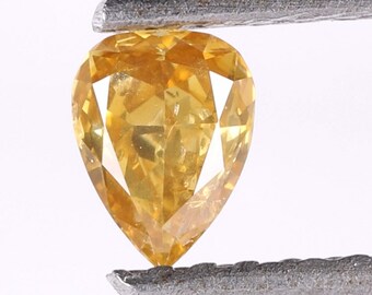 May include: A pear-shaped yellow diamond gemstone with a faceted cut. The diamond is held in a pair of tweezers.