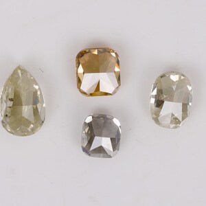 Puede incluir: Cuatro diamantes sueltos de diferentes formas y tama&ntilde;os. Los diamantes son de forma de pera, de talla coj&iacute;n cuadrada y de talla coj&iacute;n redonda. Los diamantes son todos de color amarillo claro.