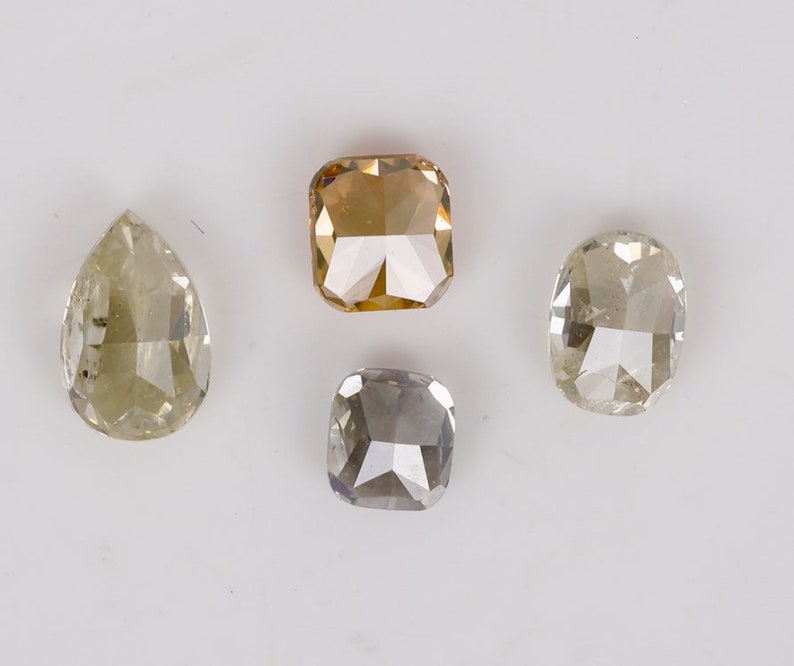 Puede incluir: Cuatro diamantes sueltos de diferentes formas y tama&ntilde;os. Los diamantes son de forma de pera, de talla coj&iacute;n cuadrada y de talla coj&iacute;n redonda. Los diamantes son todos de color amarillo claro.