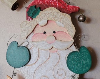 May include: Wooden Santa Claus Christmas decoration with the text "WE BELIEVE IN SANTA". The Santa figure has a white beard, a red hat, and green accents. Includes a star, heart, and bell.