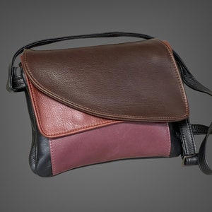May include: A small, brown, black, and burgundy leather crossbody bag with a flap closure.