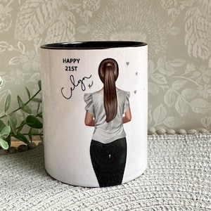 May include: White ceramic mug with a black rim. The mug features a graphic of a woman with brown hair in a ponytail, wearing a white shirt and black pants. The text "Happy 21st" and a signature are printed on the mug.