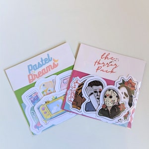 May include: Two sticker packs, one with pastel colors and the text "Pastel Dreams" and the other with a pink background and the text "The Horror Pack". The horror pack includes stickers of Freddy Krueger, Jason Voorhees, and Michael Myers.
