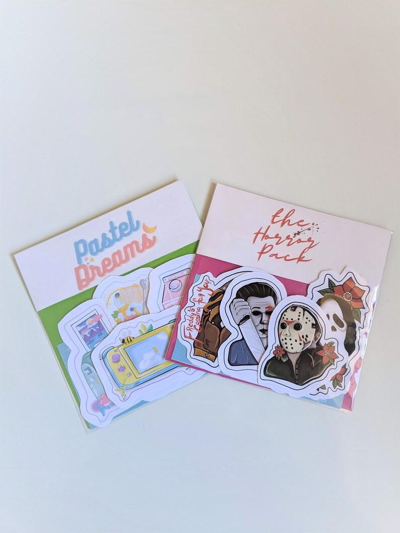 May include: Two sticker packs, one with pastel colors and the text "Pastel Dreams" and the other with a pink background and the text "The Horror Pack". The horror pack includes stickers of Freddy Krueger, Jason Voorhees, and Michael Myers.