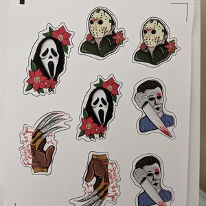 K&ouml;nnte beinhalten: Acht Horrorfilm-Charakter-Aufkleber mit Freddy Krueger, Jason Voorhees und Ghostface. Die Aufkleber sind auf wei&szlig;em Papier gedruckt und zeigen rote und wei&szlig;e Stechpalmenmotive.