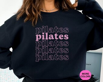 May include: Black sweatshirt with the word "pilates" repeated five times in pink lettering.