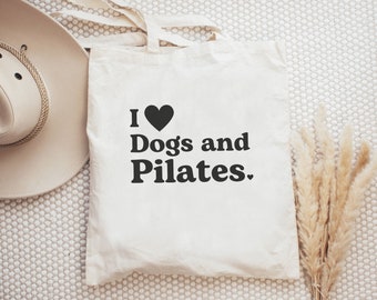 May include: White canvas tote bag with black text that reads "I love Dogs and Pilates."