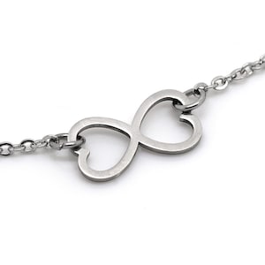 Könnte beinhalten: Eine silberne Halskette mit einem Anhänger in Form eines Doppelherzens mit Unendlichkeitszeichen.