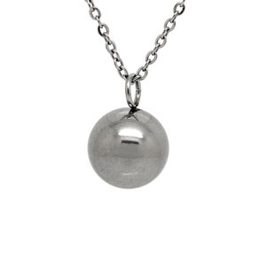 Puede incluir: Un collar de cadena de plata con un gran colgante redondo de plata.