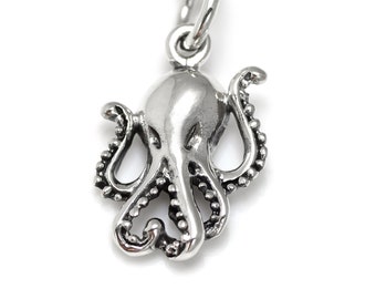 Puede incluir: Un colgante de plata en forma de pulpo con tentáculos detallados. El colgante es una pieza de joyería encantadora y única.