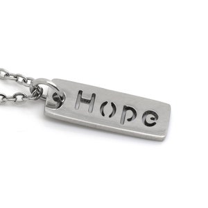 May include: A silver necklace with a rectangular pendant that says "Hope" in a cut-out font.