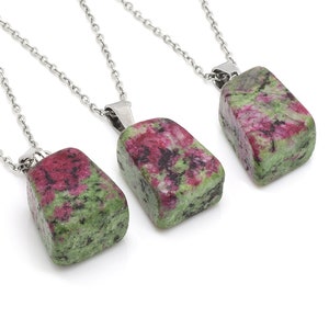 May include: Three silver chains with pendants made of green and pink natural stone. The stones are rough and have a natural, irregular shape.