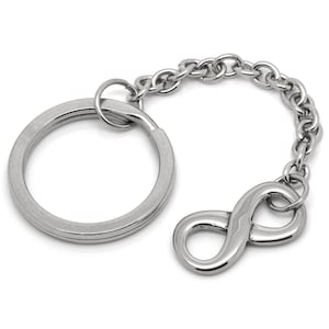 Puede incluir: Un llavero plateado con un anillo redondo y un dije con el símbolo del infinito.
