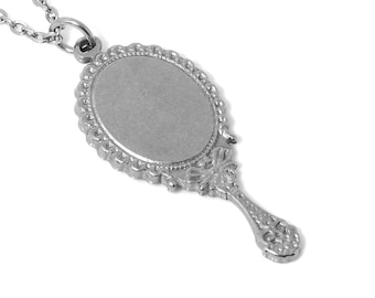 May include: A silver necklace featuring a decorative hand mirror pendant. The mirror is oval shaped with a scalloped edge and a bow detail at the top. The pendant is attached to a silver chain.