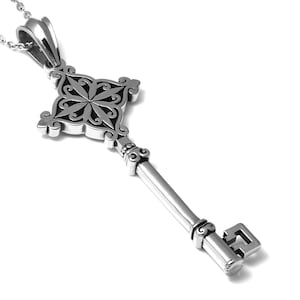 May include: A silver key pendant necklace with an ornate, intricate design. The key has a square head with a floral pattern and a long, slender shaft.