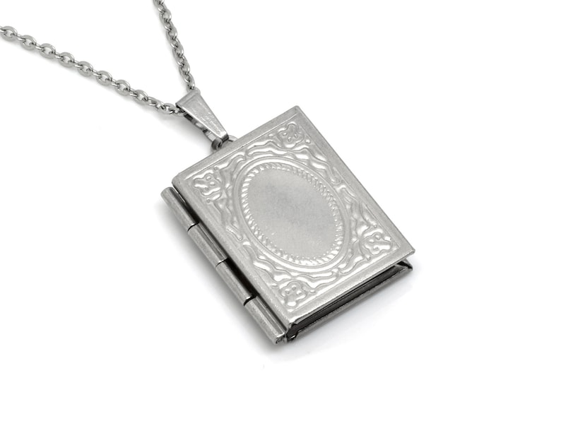 May include: A silver locket necklace with a detailed engraved design. The locket has a hinged opening and a smooth oval inside.