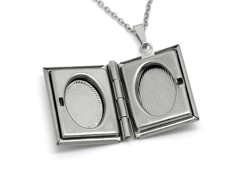May include: Silver locket necklace with two oval-shaped photo compartments. The locket is open, revealing the empty compartments.