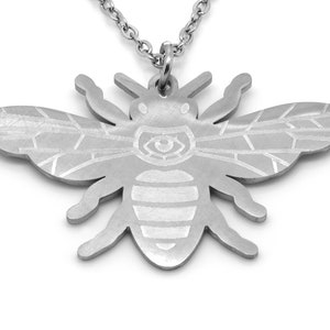 Könnte beinhalten: Eine silberne Bienen-Anhänger-Kette mit einem detaillierten, geätzten Design. Die Biene ist ein beliebtes Symbol für harte Arbeit und Gemeinschaft.
