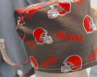 May include: Brown and white surgical scrub hat with a repeating pattern of brown football helmets and the word "Browns" in red.