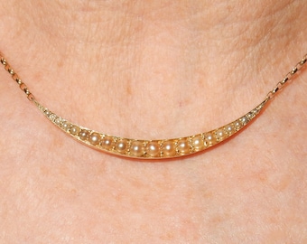 Op de afbeelding: Een gouden ketting met een halve maanvorm gemaakt van kleine parels.
